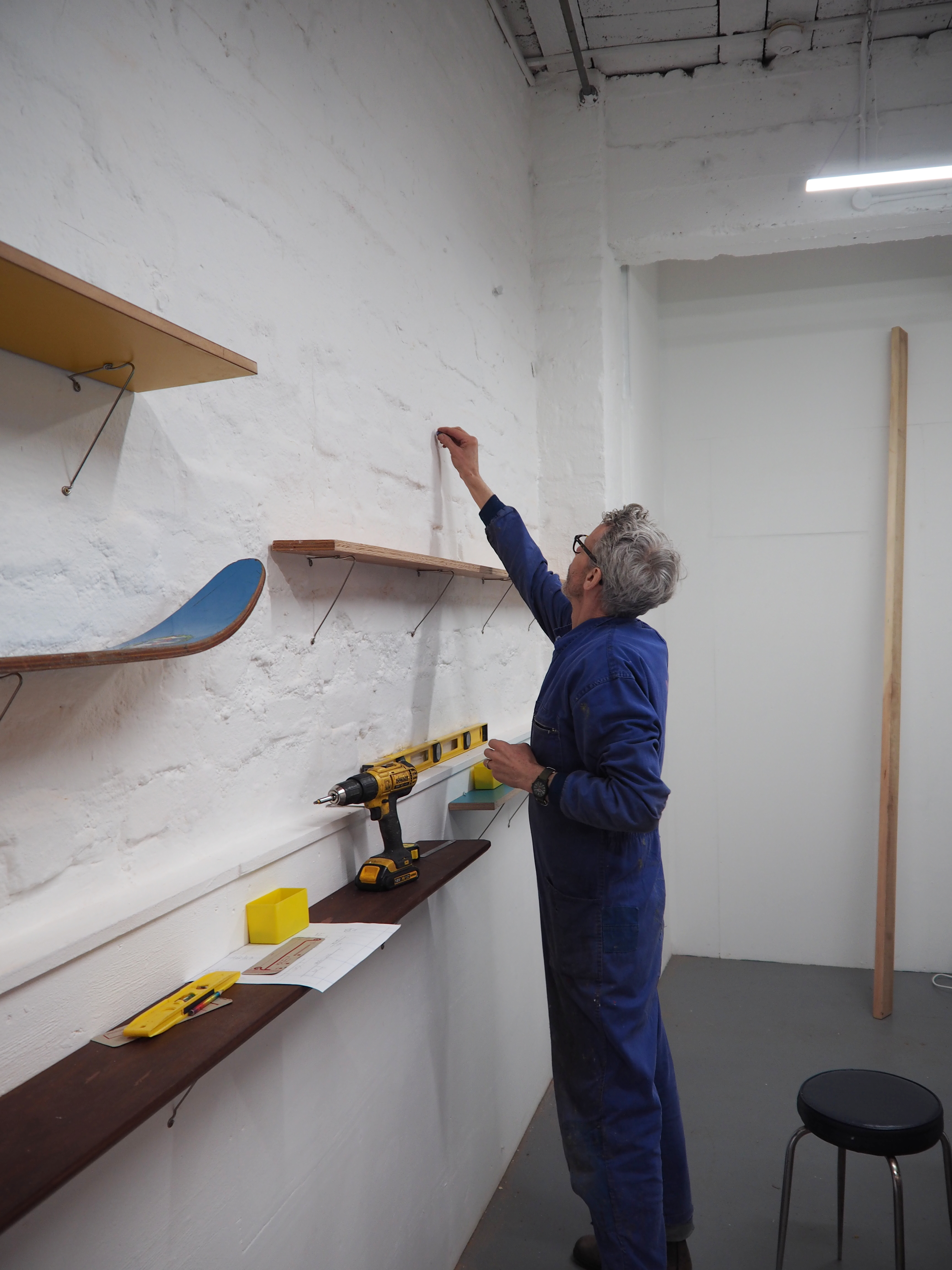 Michael Marriott putting up shelves on a gallery wall
