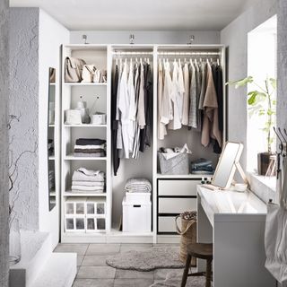walk in closet with open shelving/hanging , gray and white scheme, dressing table, stone tile floor