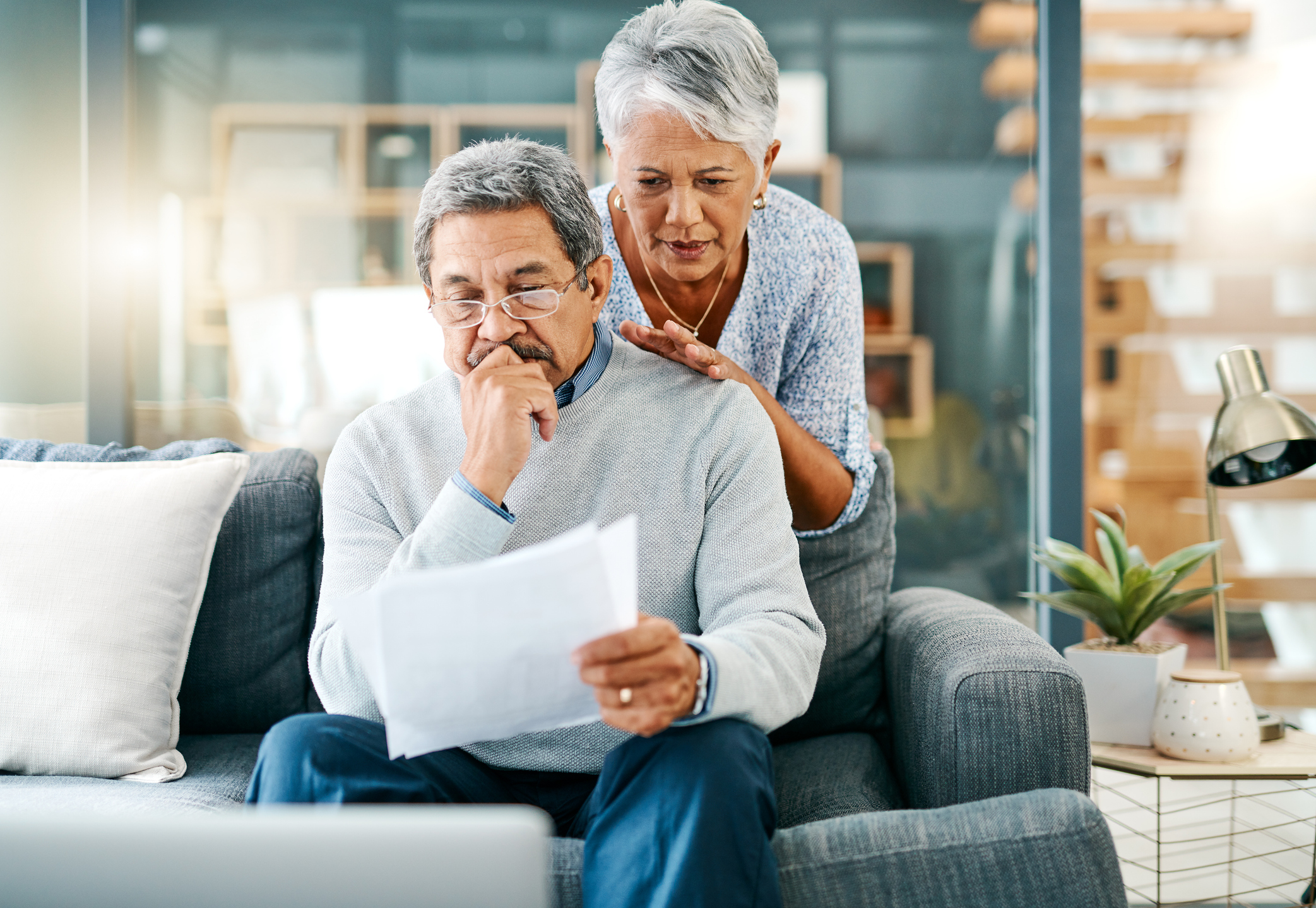 Shot of an older couple looking worried while going through paperwork together at home