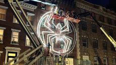 An image of a Spider-Man logo being installed on a building in downtown New York