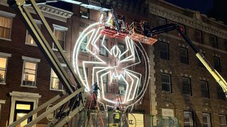 An image of a Spider-Man logo being installed on a building in downtown New York