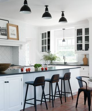 A black and white kitchen with three pendant lights and white cabinetry