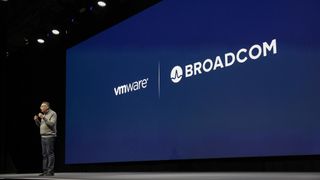 VMware CEO Raghu Raghuram, standing on the keynote stage in front of a screen bearing the VMware and Broacom logos