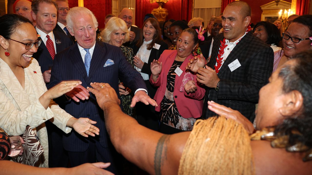 King Charles wearing a suit and dancing with a group of guests at Buckingham Palace