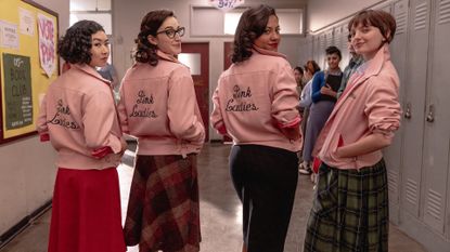 cast of Grease: Rise of the Pink Ladies in their pink jackets in a high school hallway