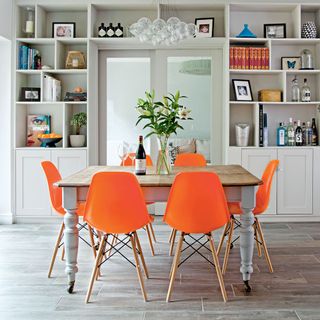 dining area with white shelves and orange chairs