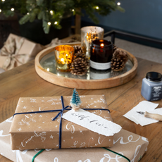 Two presents wrapped i brown paper and blue ribbon on a coffee table 