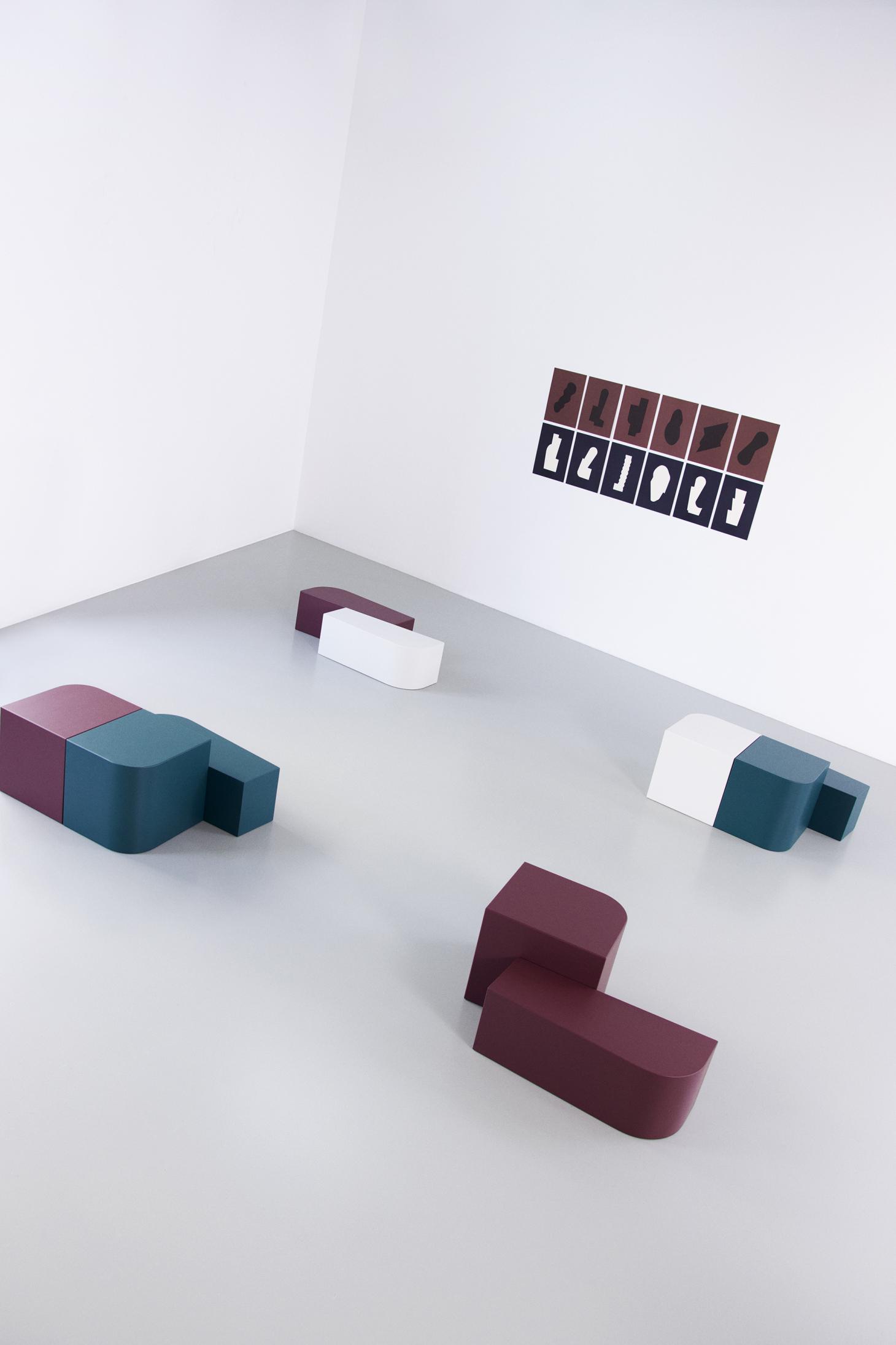 Lacquered side tables in green, burgundy, white with art posters on the wall featuring the same geometric shapes