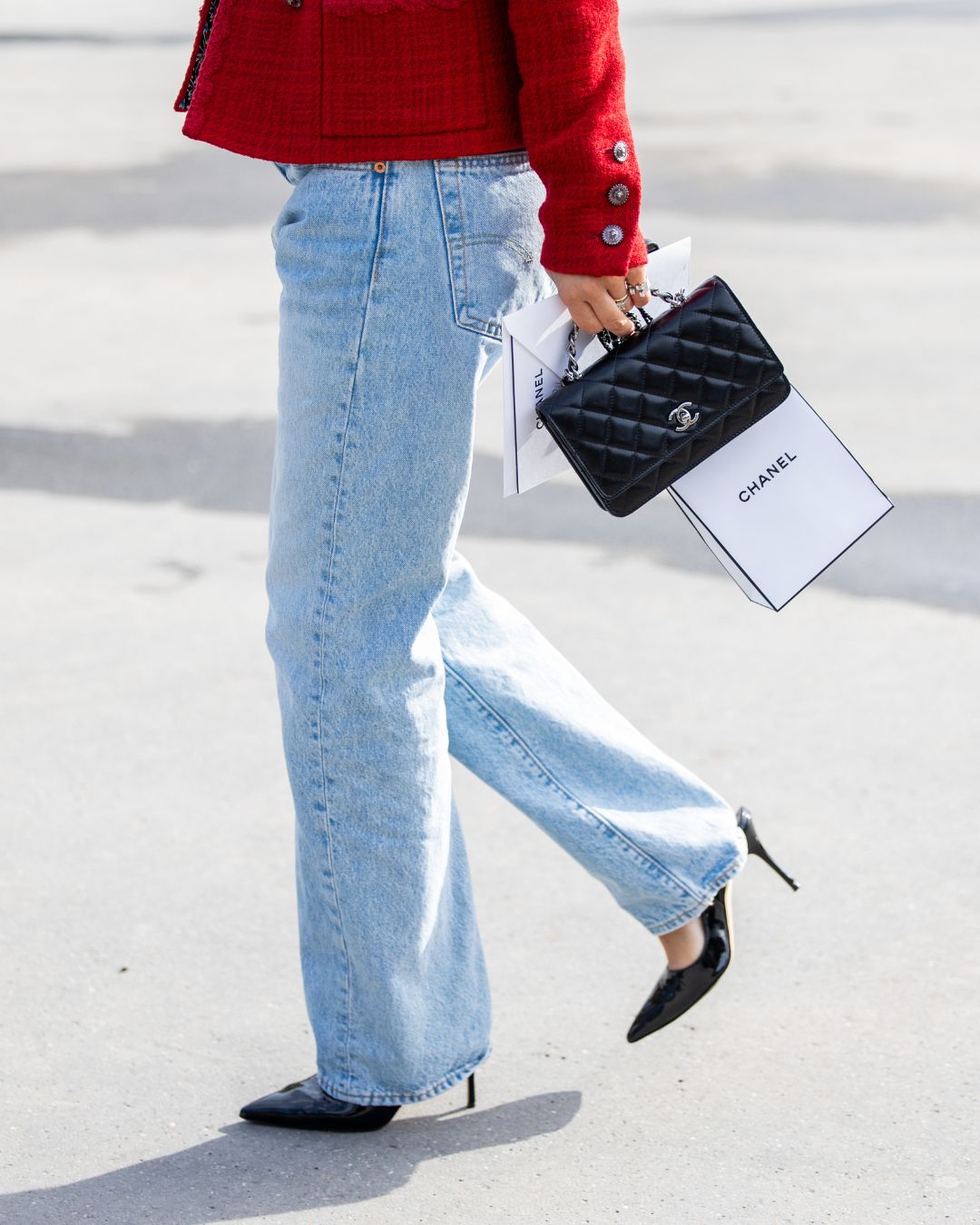a woman in jeans carrying a classic black chanel handbag