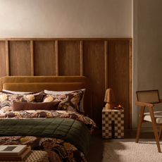 Cosy bedroom with wicker lamp on bedside table.