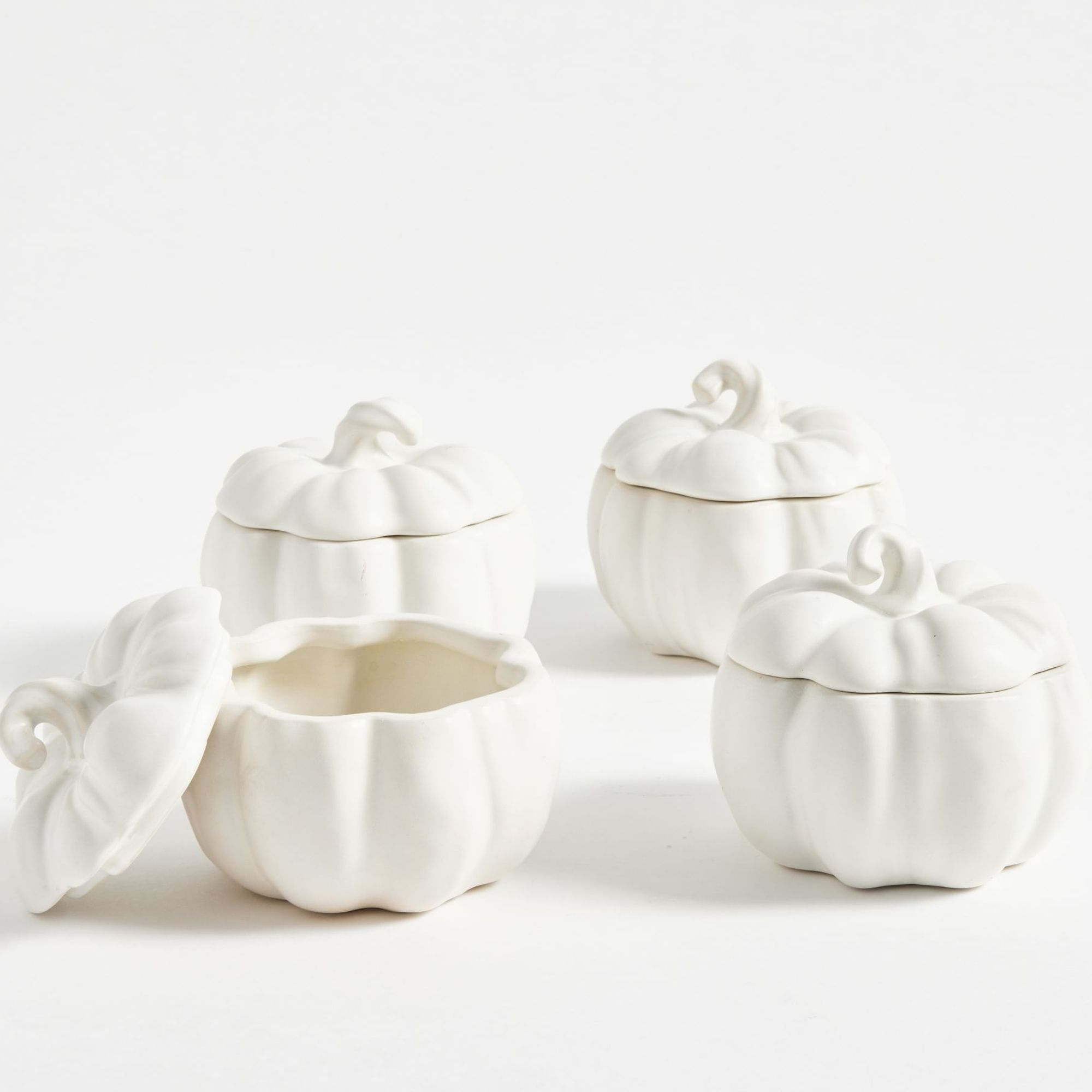 Four white pumpkin shaped tureens with lids