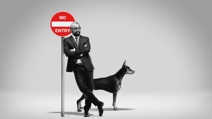 James Cleverly leaning on a No Entry sign next to Doberman