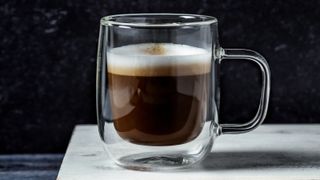 A shot of macchiato on wooden cutting board on black background - stock photo
