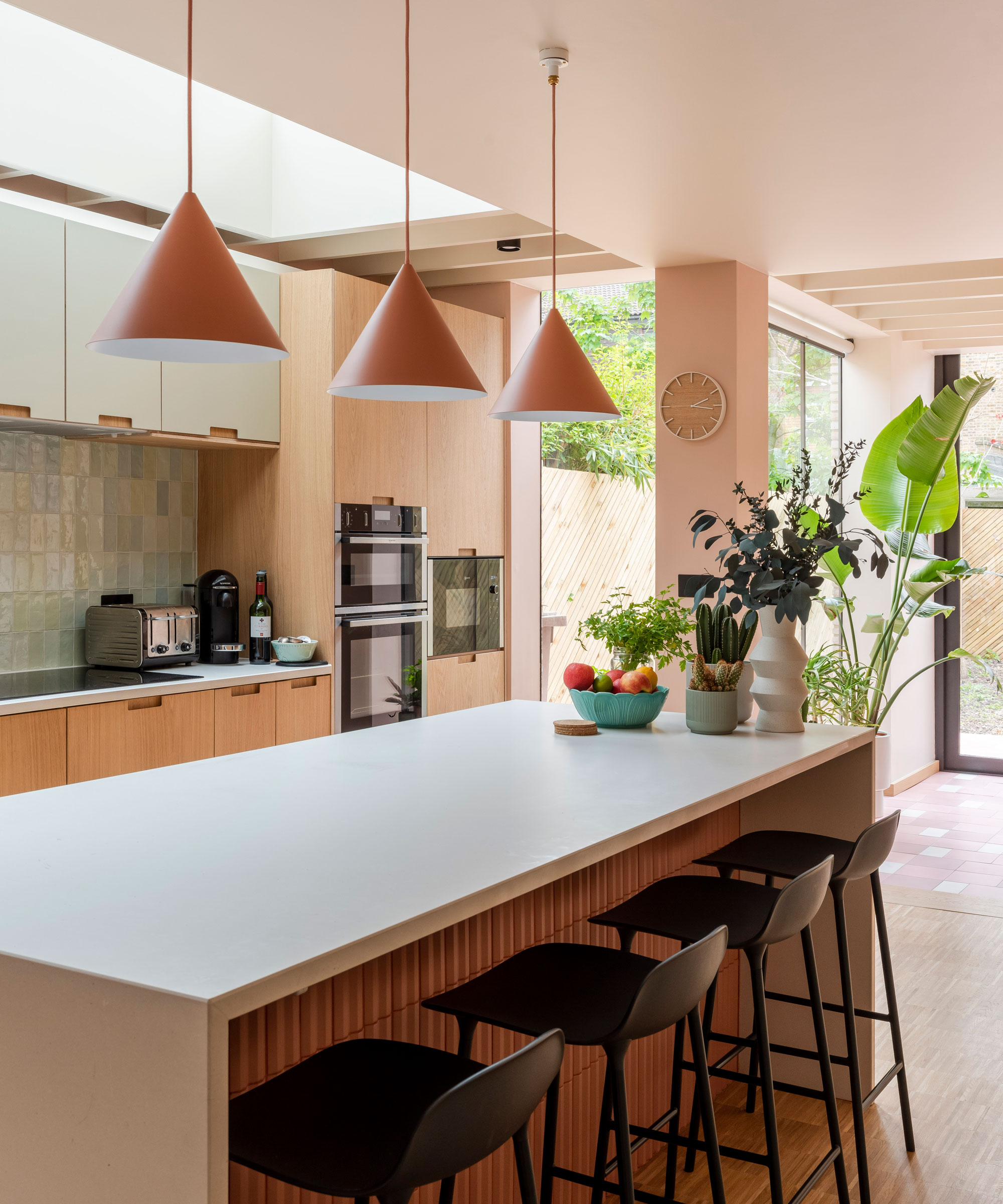 L-shaped kitchen extension with kitchen island with black bar stools