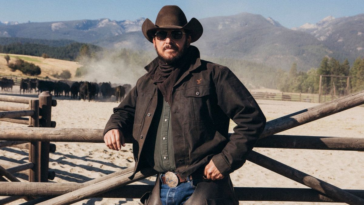 Cole Hauser as Rip standing against a fence in Yellowstone.