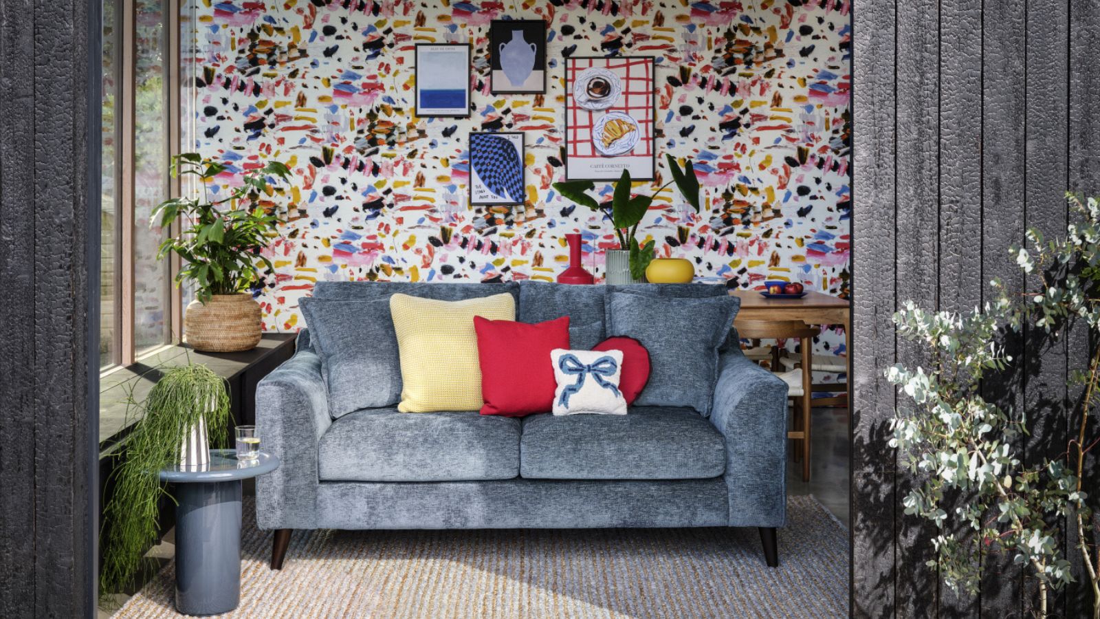 Small living room with gray sofa and colorful wallpaper and gallery