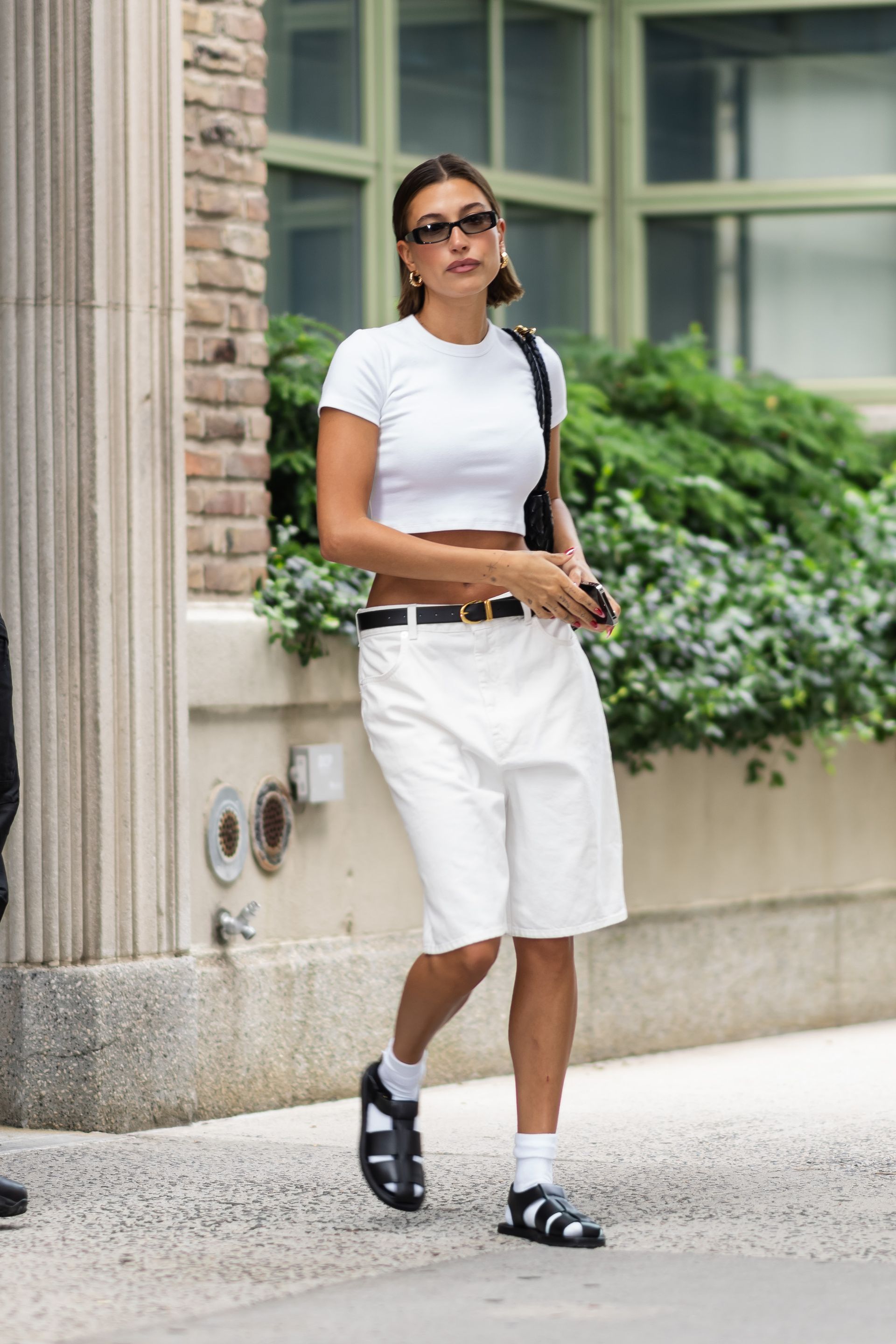 Hailey Bieber in white bermuda shorts and fisherman sandals