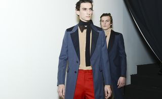Two models stood with blue jackets, red trousers and scarf around neck