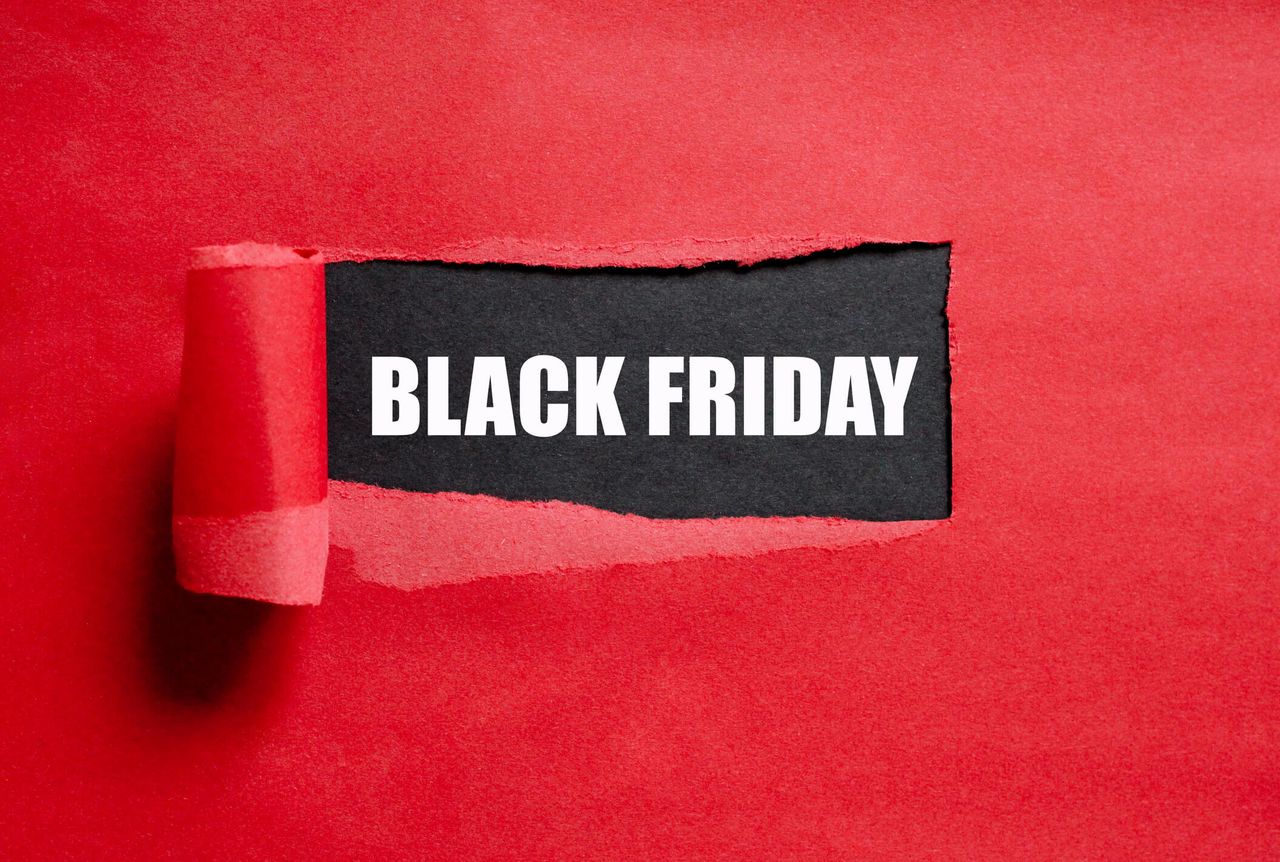 A red background with a section of paper peeled back to reveal a black piece of paper with the words BLACK FRIDAY written in white font.