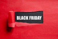 A red background with a section of paper peeled back to reveal a black piece of paper with the words BLACK FRIDAY written in white font.