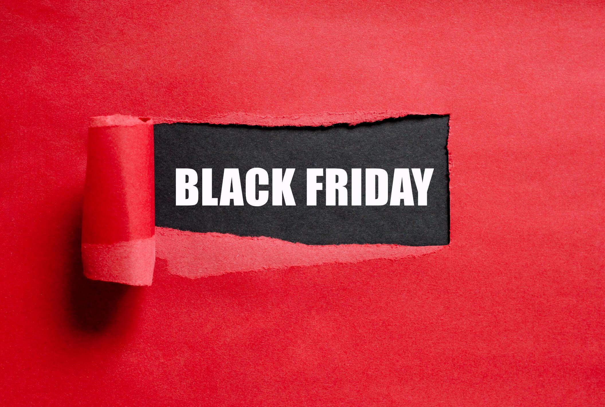  A red background with a section of paper peeled back to reveal a black piece of paper with the words BLACK FRIDAY written in white font. 