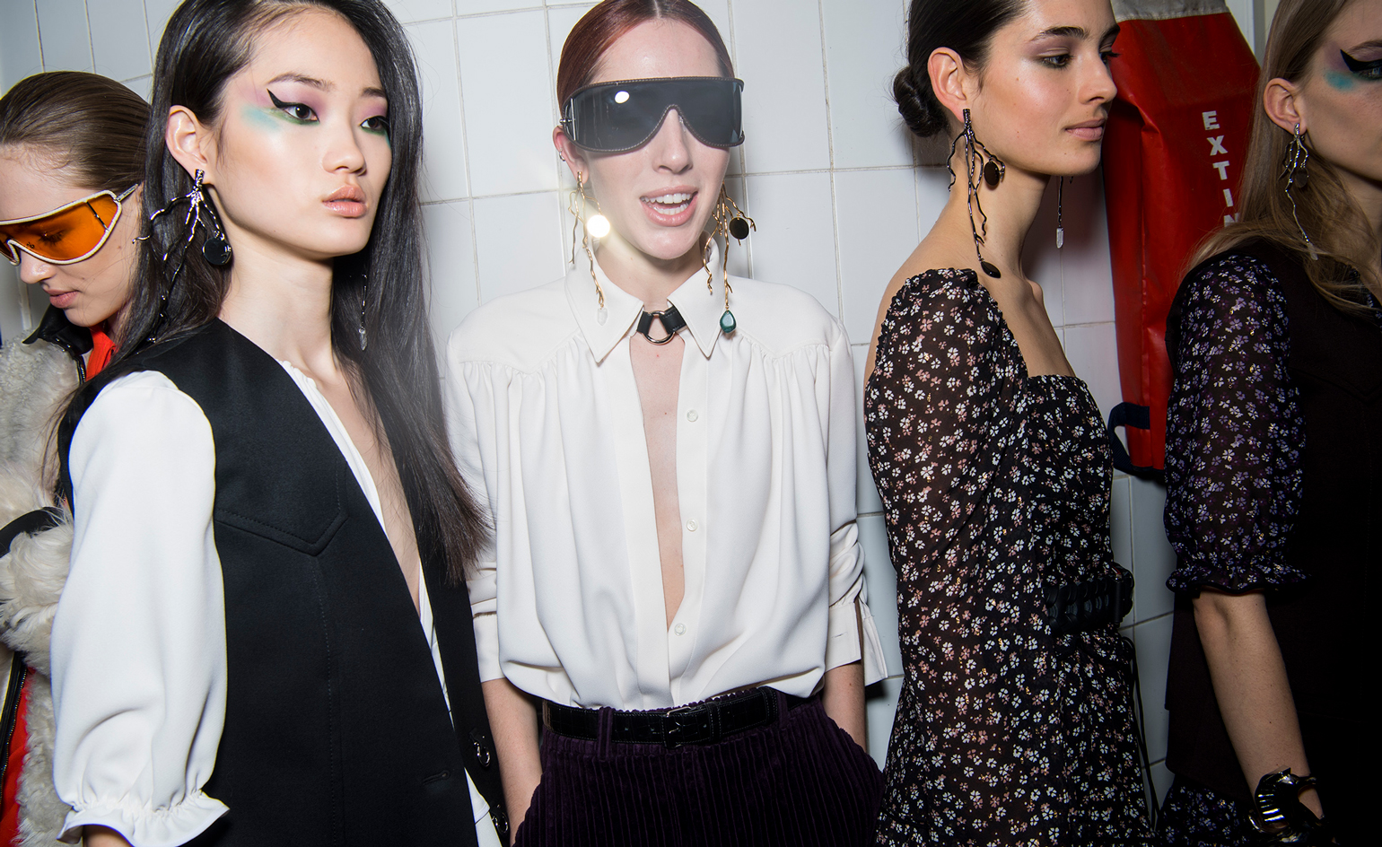 Models wear white shirts with a deep v-neck cut, others wear floral dresses in navy