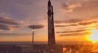 A Rocket Lab Electron booster seen at sunset in orange light.