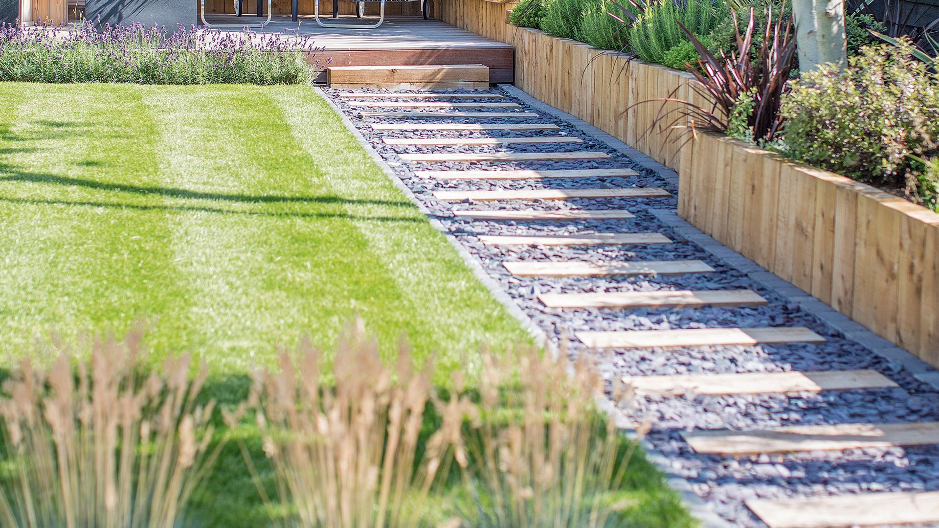 Garden with striped lawn alongside a garden path with grass flower beds
