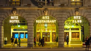 The front entrance of the Ritz Hotel, London, lit up at night.