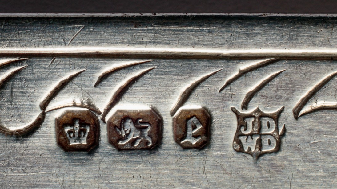 Sheffield silver hallmark 1897 James Deakin silversmith. British silver, if sterling (92.5% silver), has a standard set of hallmarks that verify the purity of the metal used in the hallmarked object. In this case, the four marks identify the town that gave the mark, the purity of the silver, the date letter, and the maker. In order, these are the crown for Sheffield; the lion passant for sterling silver; the letter 'e' for 1897, and the makers' mark (JD over WD, in a shield) for James Deakin and Sons. The firm was established in 1865. The item carrying these marks is a silver table knife.