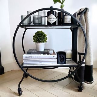 round black frame bar cart with books plant pots glasses and bottles