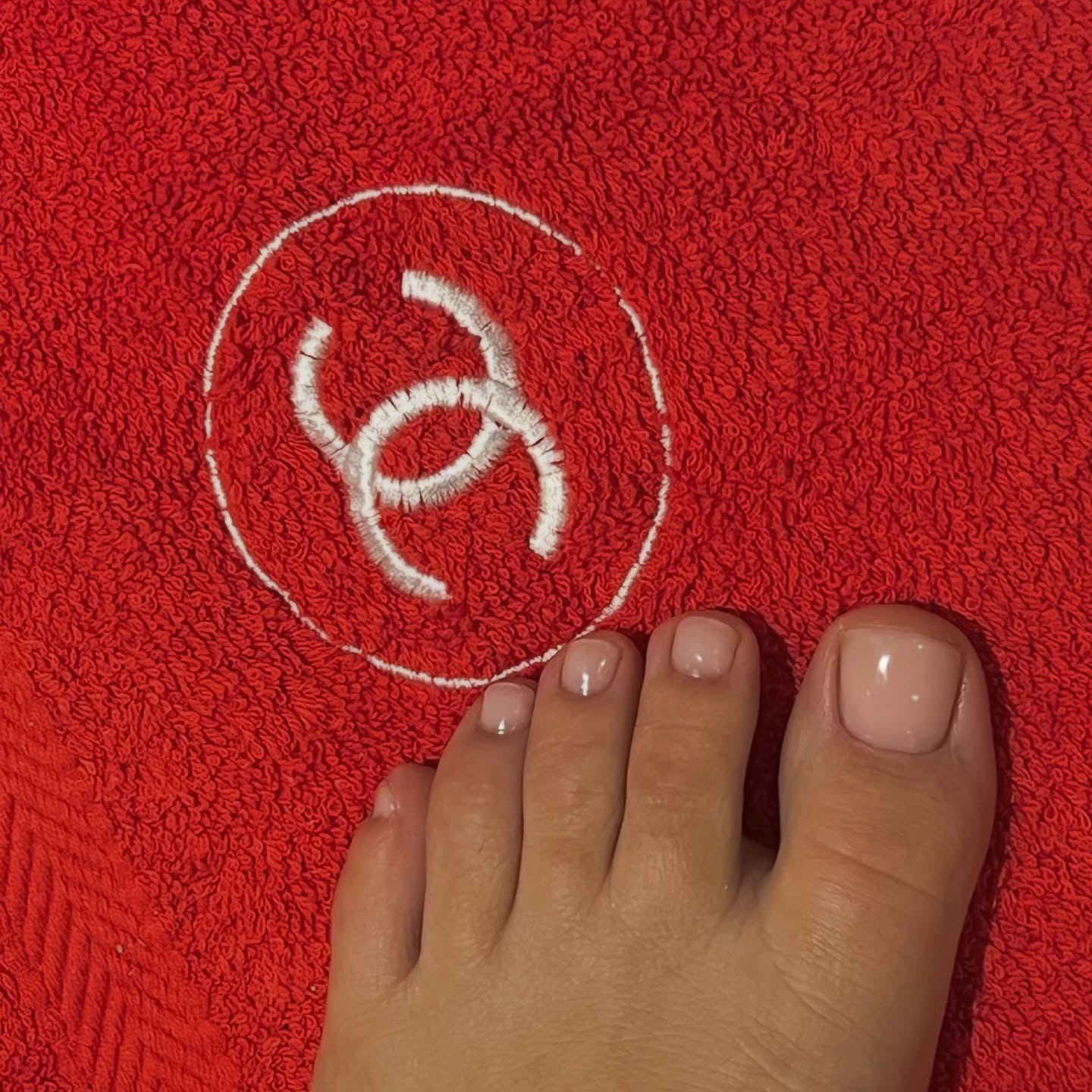 A sheer pedicure photographed on top of a red Chanel towel