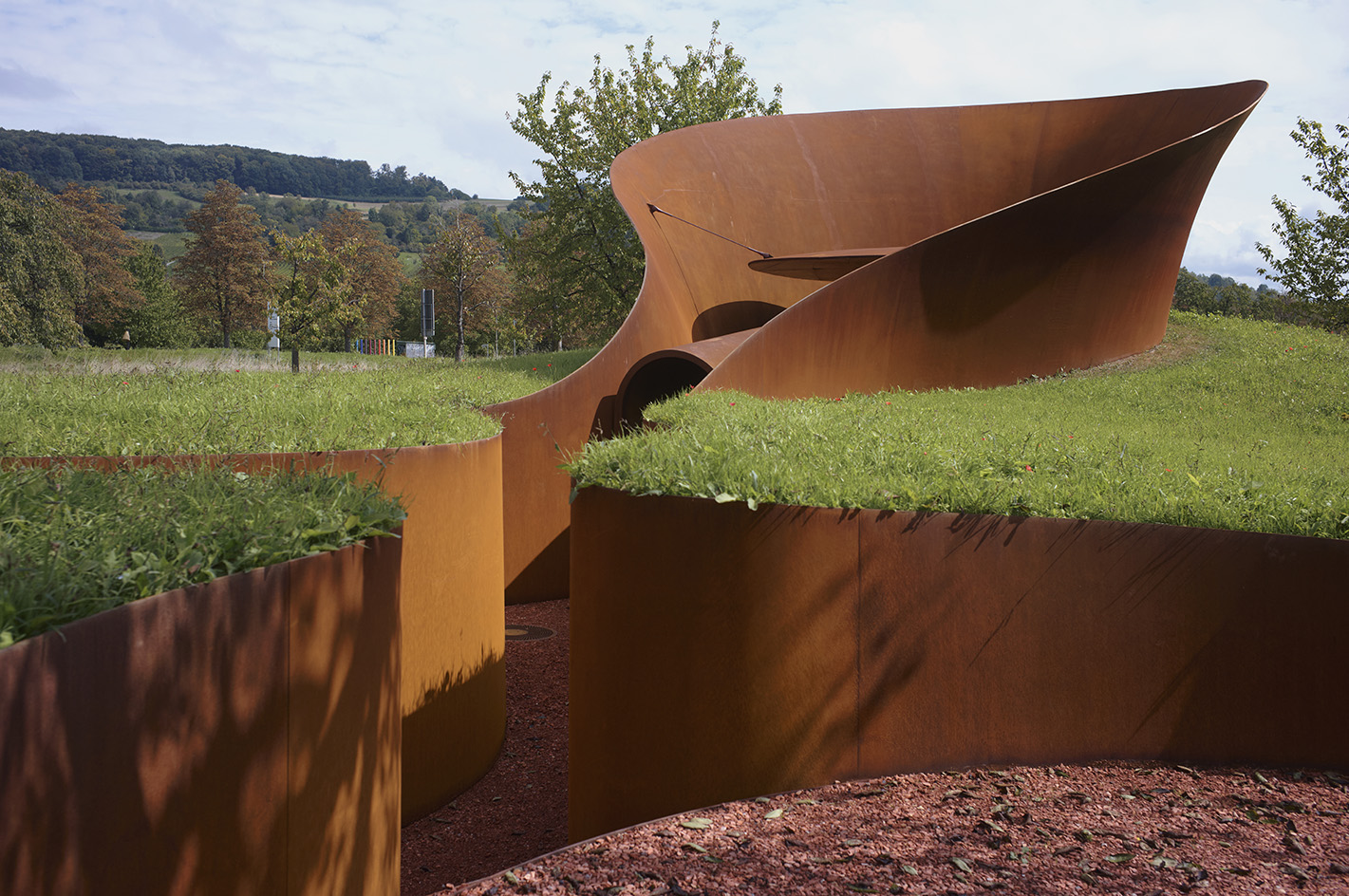 Doshi Retreat at Vitra, a pavilion made of corten steel and minimalist forms seen in the green countryside