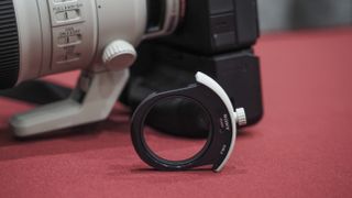 Sony FE 300mm f/2.8 GM OSS lens on a red table with grey curtains