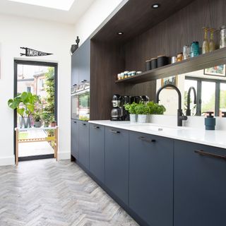 one line navy galley style kitchen in an extension with rooflights overhead and fixed glazing to bring in light