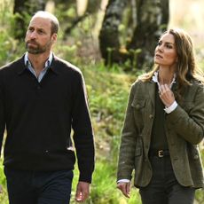 Prince William wears a V-neck sweater with a blue shirt underneath and Kate Middleton wears a green jacket