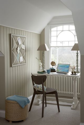 bedroom office in front of window, shiplap walls painted cream, modern chair, basket, white desk, pin board