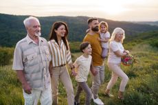 Happy family enjoying a summer walk on a hill at golden hour