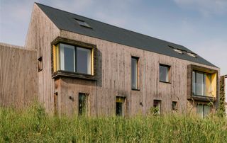 exterior of eco timber clad home with slate roof set in green countryside