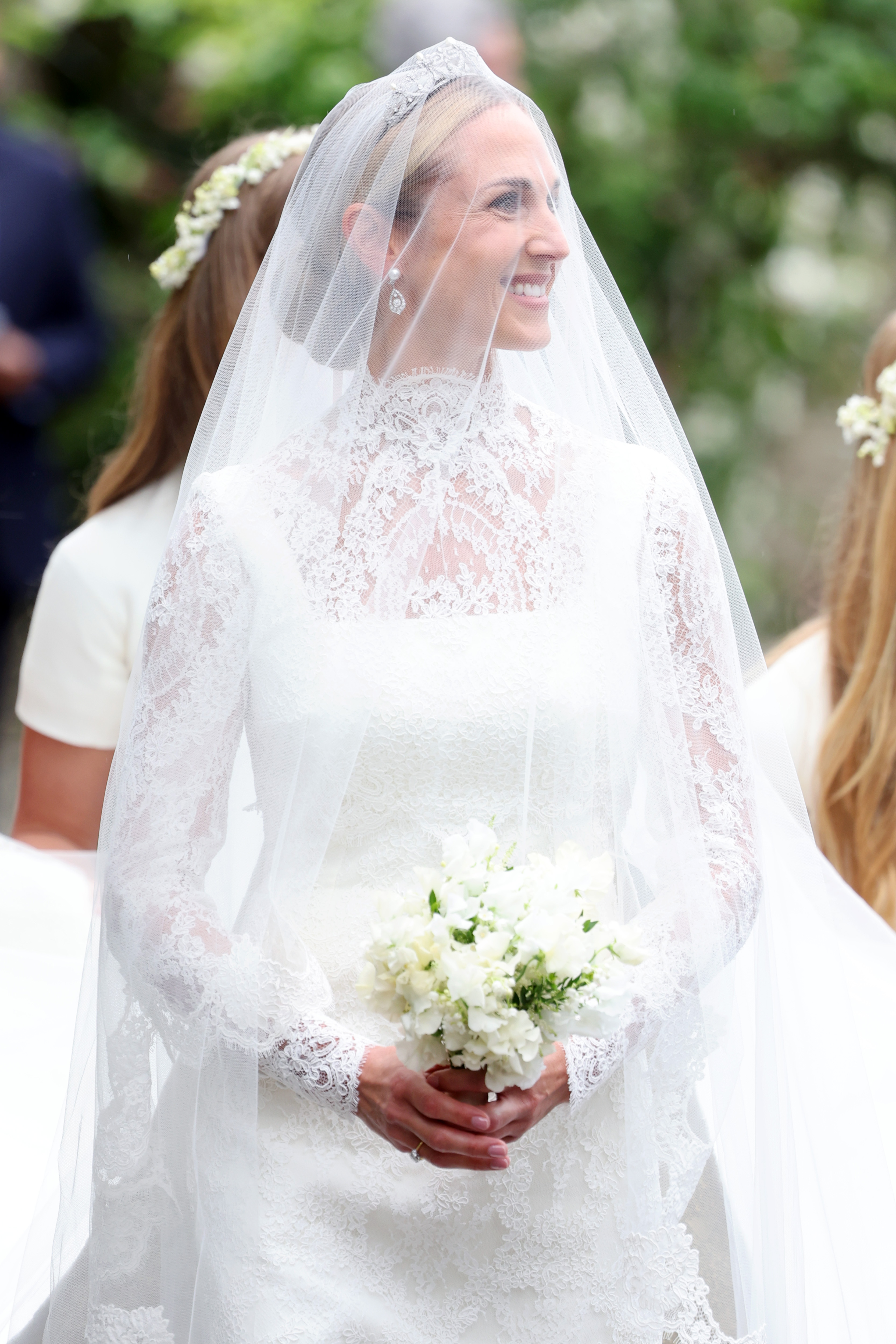 Harriet Sperling arrives at her royal wedding to Princess Anne's son wearing a white column gown featuring long lace sleeves, a tiara, and a long veil