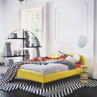 Bright room with yellow, black and white bed and round bookshelf