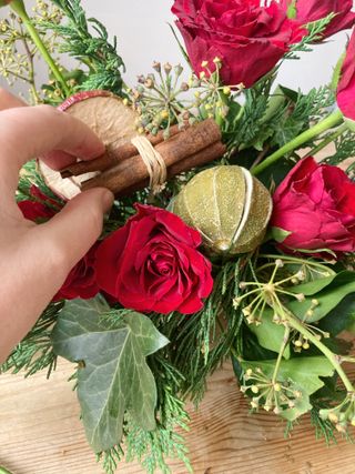 Christmas table centerpiece step by step, adding in dried fruit, pine cones and cinnamon sticks