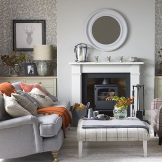 small grey living room with sofa with orange cushions