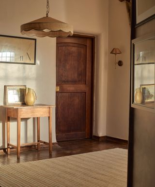 hallway with wooden floor, jute rug, wooden sidetable and jute pendant light