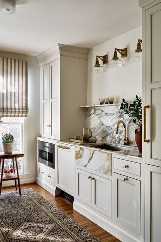 A kitchen showcasing vintage lights, white cabinets and a kitchen rug