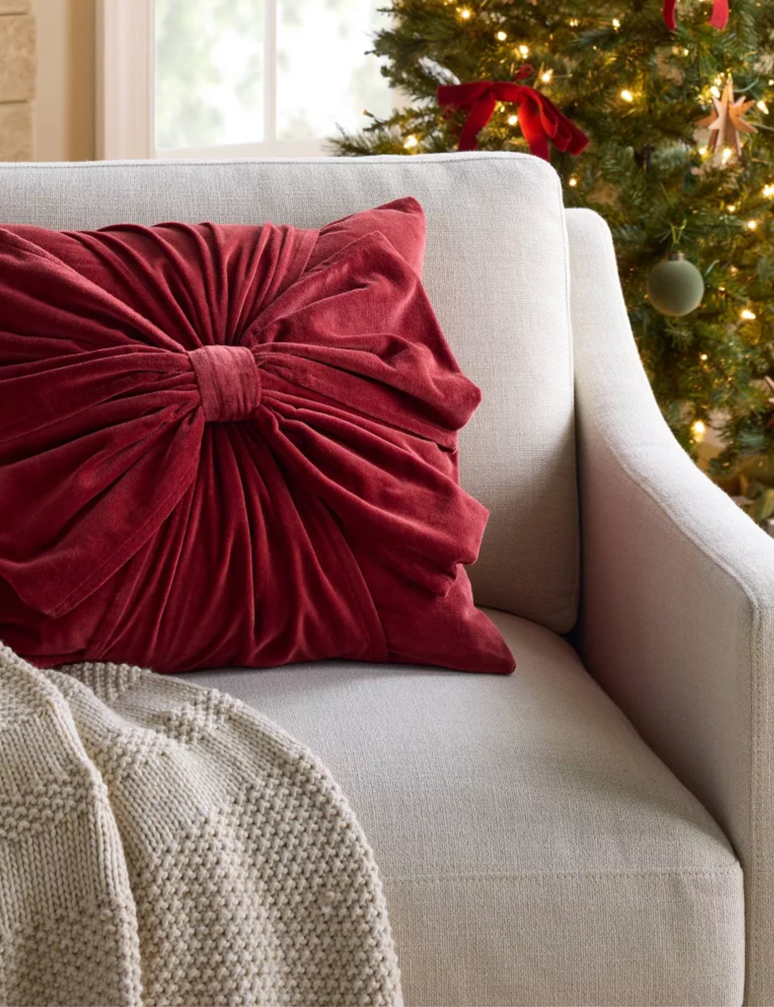 Red velvet bow motif throw pillow styled on a grey armchair