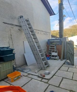 A ladder, step ladder and tools outside a listed building
