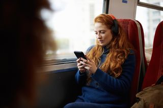A woman sat on a train using her mobile phone