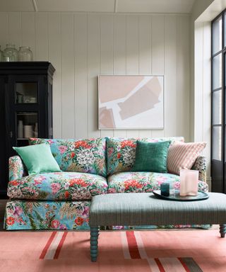 living room with blue floral sofa pink rug and black cabinet and artwork