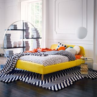 white bedroom with dark flooring and yellow bed